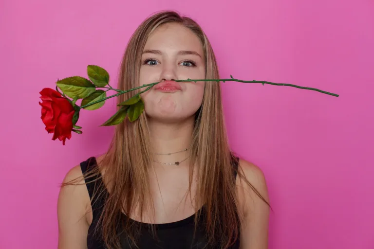 Teen girl posing for her studio portrait with a rose as a mustache. Taken at a studio in Los Angeles.