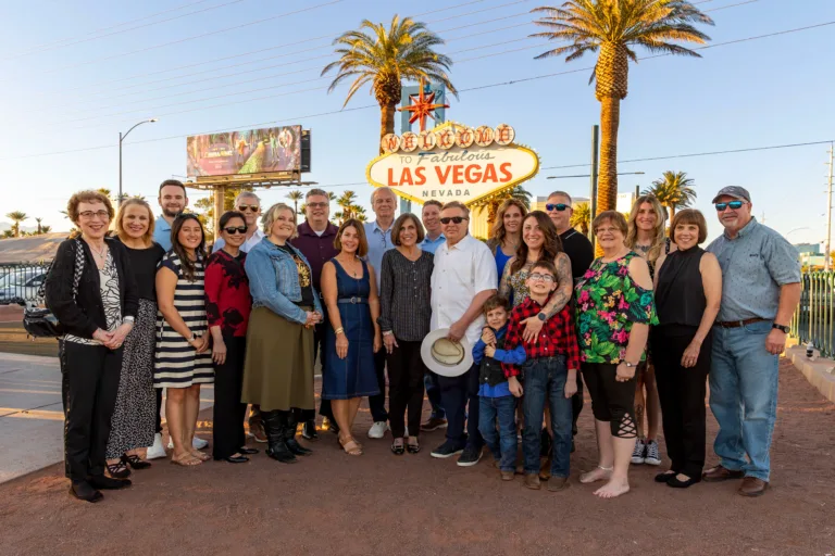 Large family photo happily posing in front of the Las Vegas Sign together.