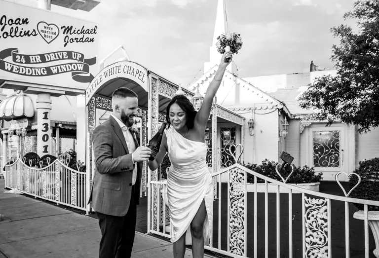 Newlywed couple popping champagne outside the Little White Wedding Chapel in Las Vegas